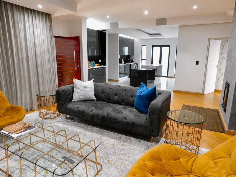 Modern open-plan living area featuring a sleek kitchen with island, hardwood flooring, and a built-in fireplace, creating a sophisticated and cohesive living space.