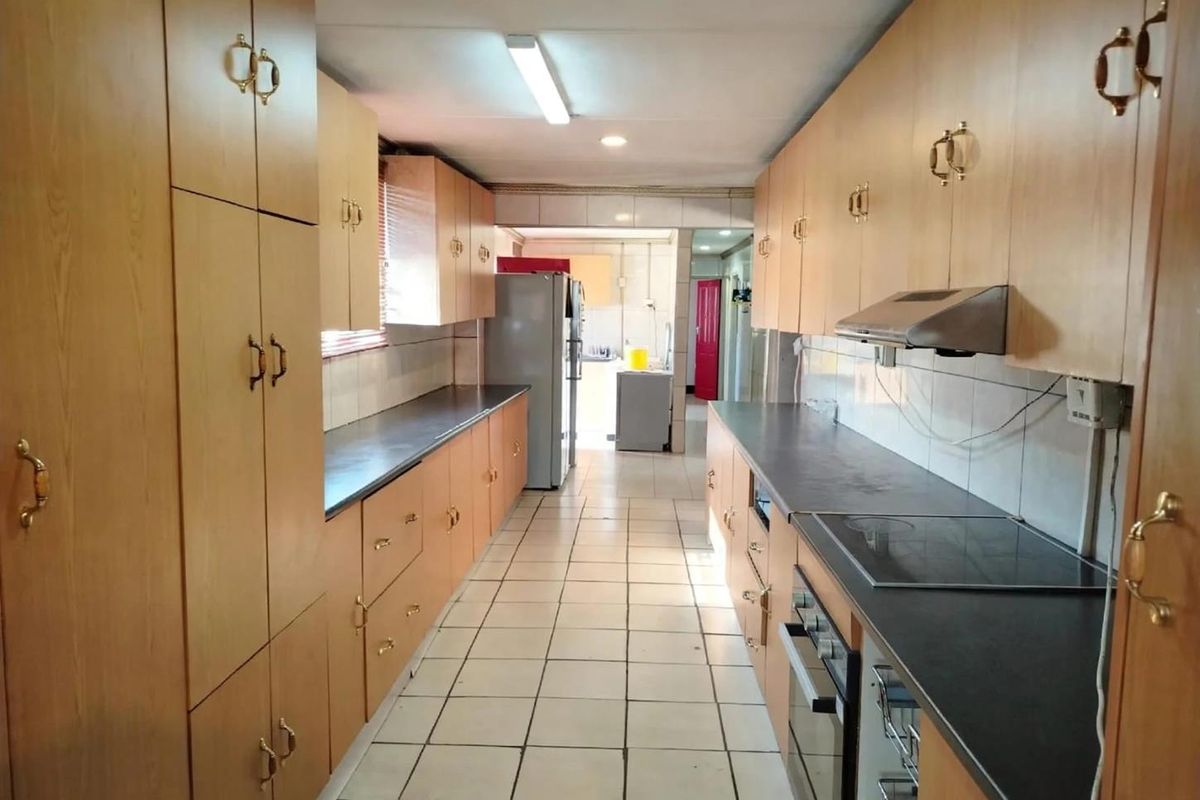 A functional galley-style kitchen featuring extensive laminate cabinetry, built-in oven, electric cooktop, and tiled flooring throughout.