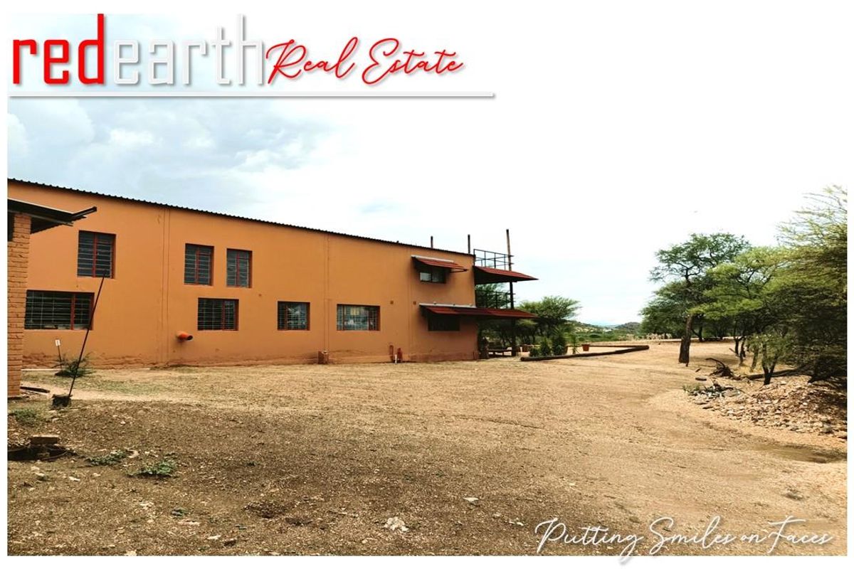 Exterior view of the lodge building featuring a multi-level structure with metal window security bars and a large surrounding gravel yard.