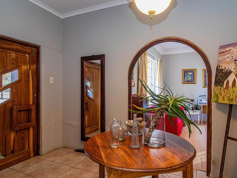 Welcoming entrance hall featuring a solid wood front door, tiled flooring, and a distinctive arched doorway leading into the living area.