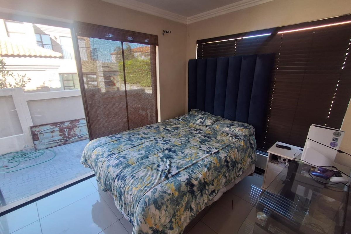 A bedroom featuring large sliding glass doors with access to an outdoor patio area, tiled flooring, and neutral wall finishes.