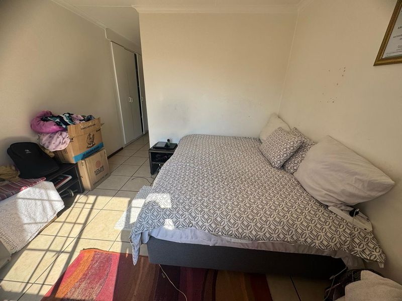 A bedroom featuring tiled flooring and built-in cupboards, offering a functional space with potential for cosmetic updates to the wall finishes.