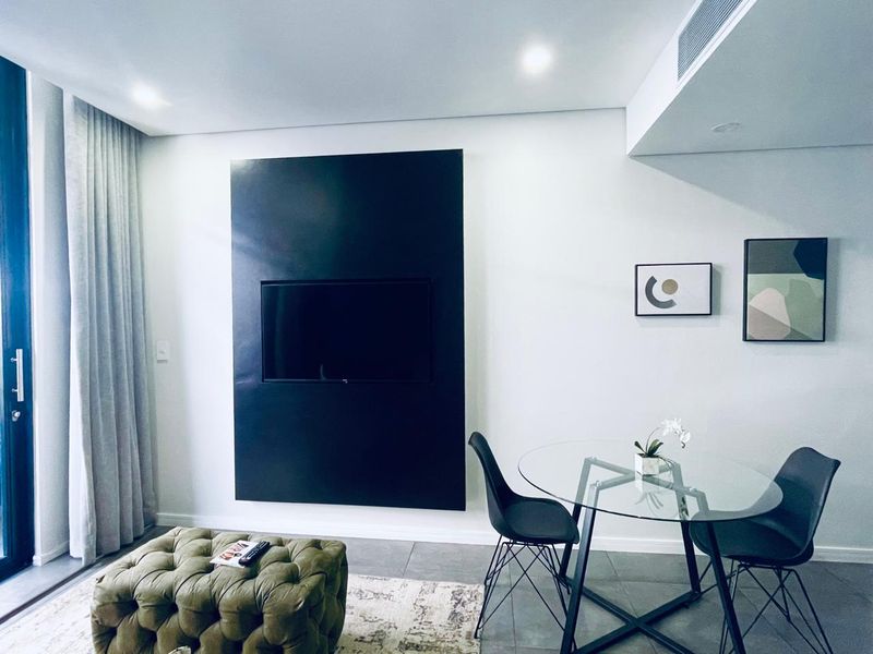Modern living area featuring tiled floors, recessed lighting, ducted air conditioning, and a sleek built-in television wall panel with access to a balcony.