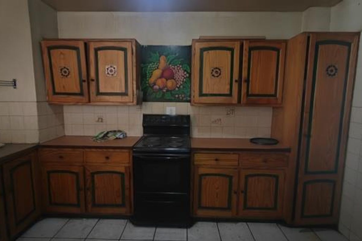 A dated kitchen featuring traditional wooden cabinetry, a built-in stove, and tiled backsplash, offering a functional layout ready for modernization.