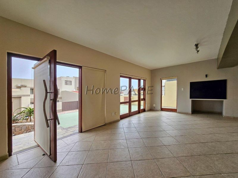 Spacious living area featuring tiled flooring, a built-in fireplace, and multiple timber-framed glass doors providing direct access to the outdoor patio area.
