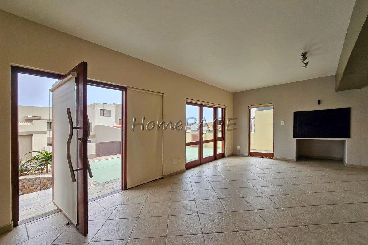 Spacious living area featuring tiled flooring, a built-in fireplace, and multiple timber-framed glass doors providing direct access to the outdoor patio area.