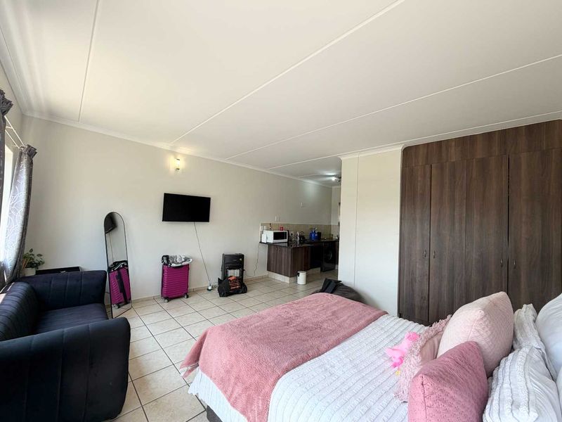 Open-plan studio apartment featuring tiled flooring, built-in storage cupboards, and a compact kitchen area.