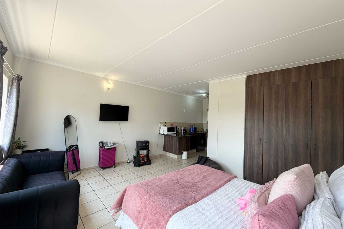 Open-plan studio apartment featuring tiled flooring, built-in storage cupboards, and a compact kitchen area.
