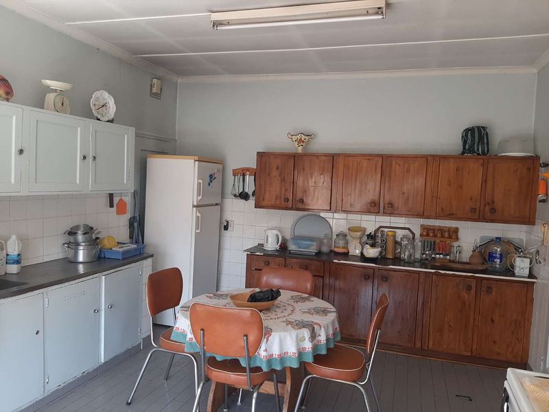 A dated kitchen featuring original wooden cabinetry, tiled backsplash, and functional layout, offering significant potential for modernization and renovation.