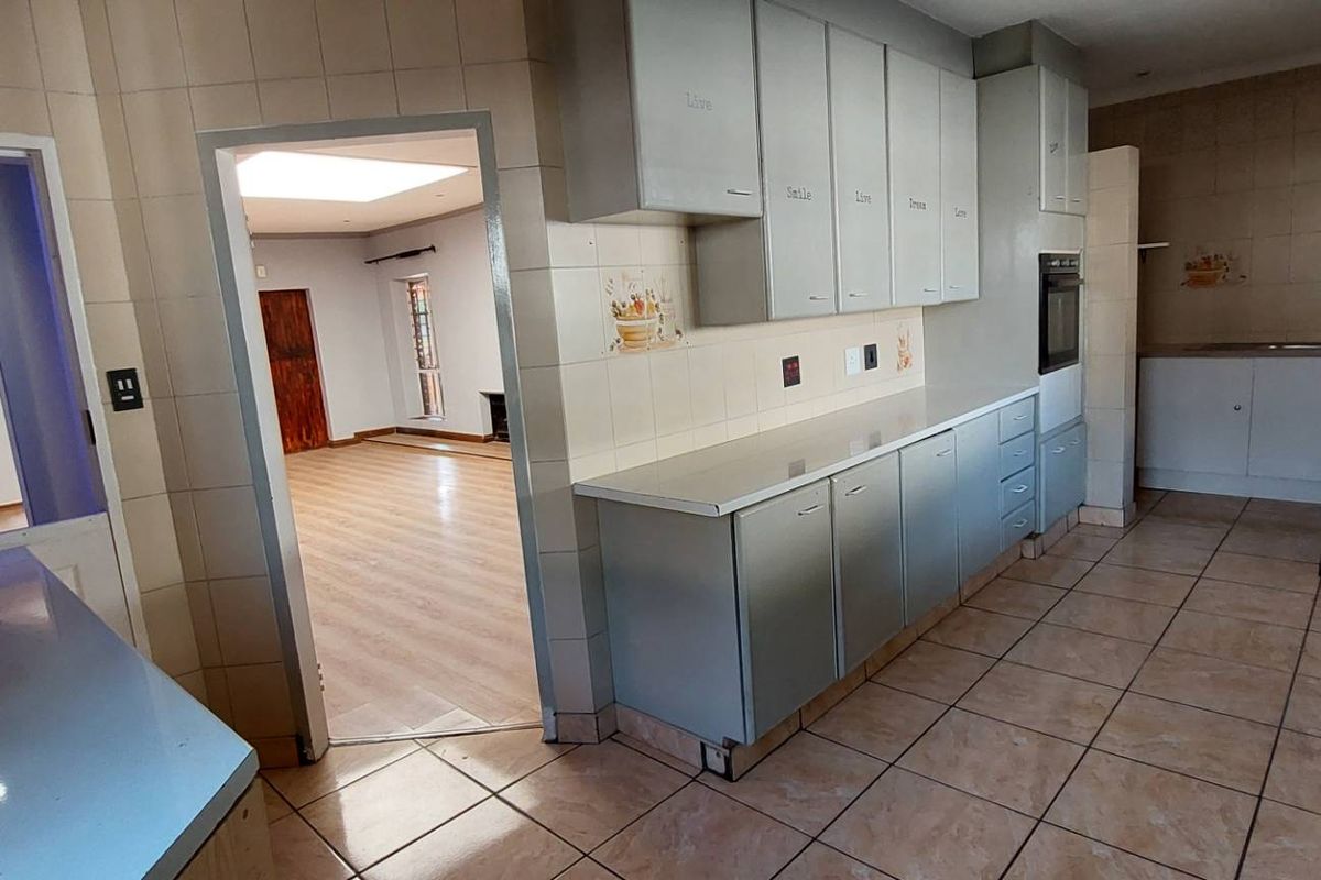 A functional kitchen featuring built-in cabinetry, tiled flooring, and integrated oven, with an open layout connecting to the adjacent living area.