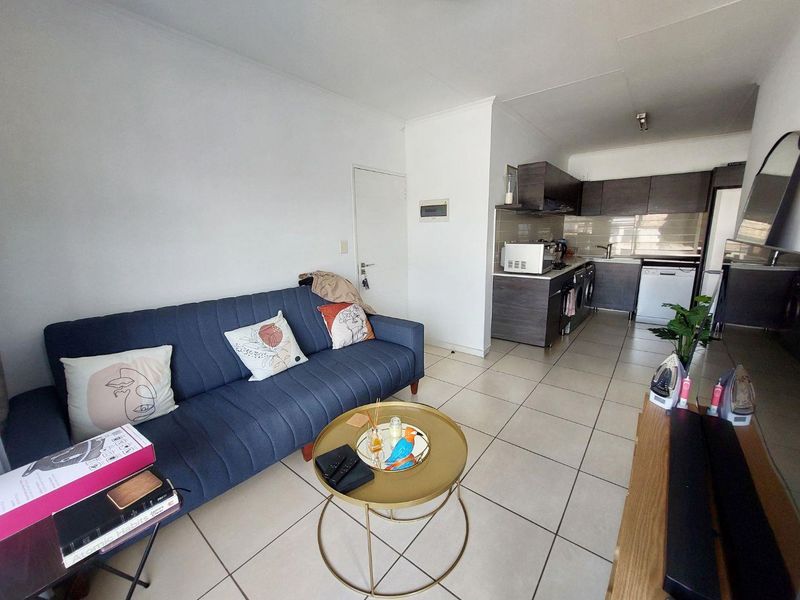 Open-plan living area featuring tiled flooring and a modern kitchen with built-in cabinetry, oven, and hob.