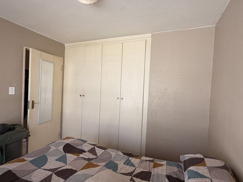 A bedroom featuring a built-in wardrobe with white doors and a standard internal door.