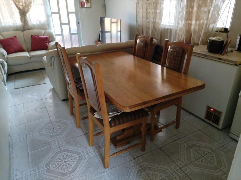 An open-plan living and dining area featuring tiled flooring and a security gate, providing a functional space for daily living.