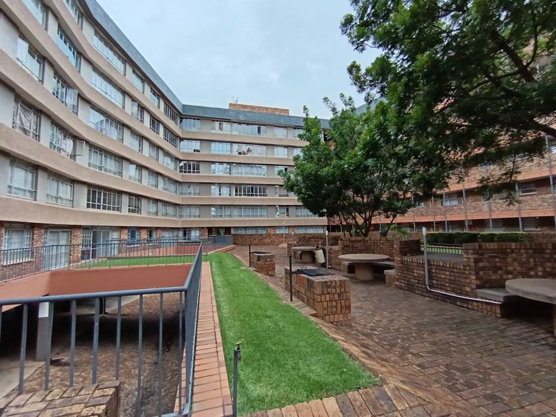 Communal outdoor courtyard area featuring brick paving, built-in brick seating, and landscaped lawn space within an apartment complex.