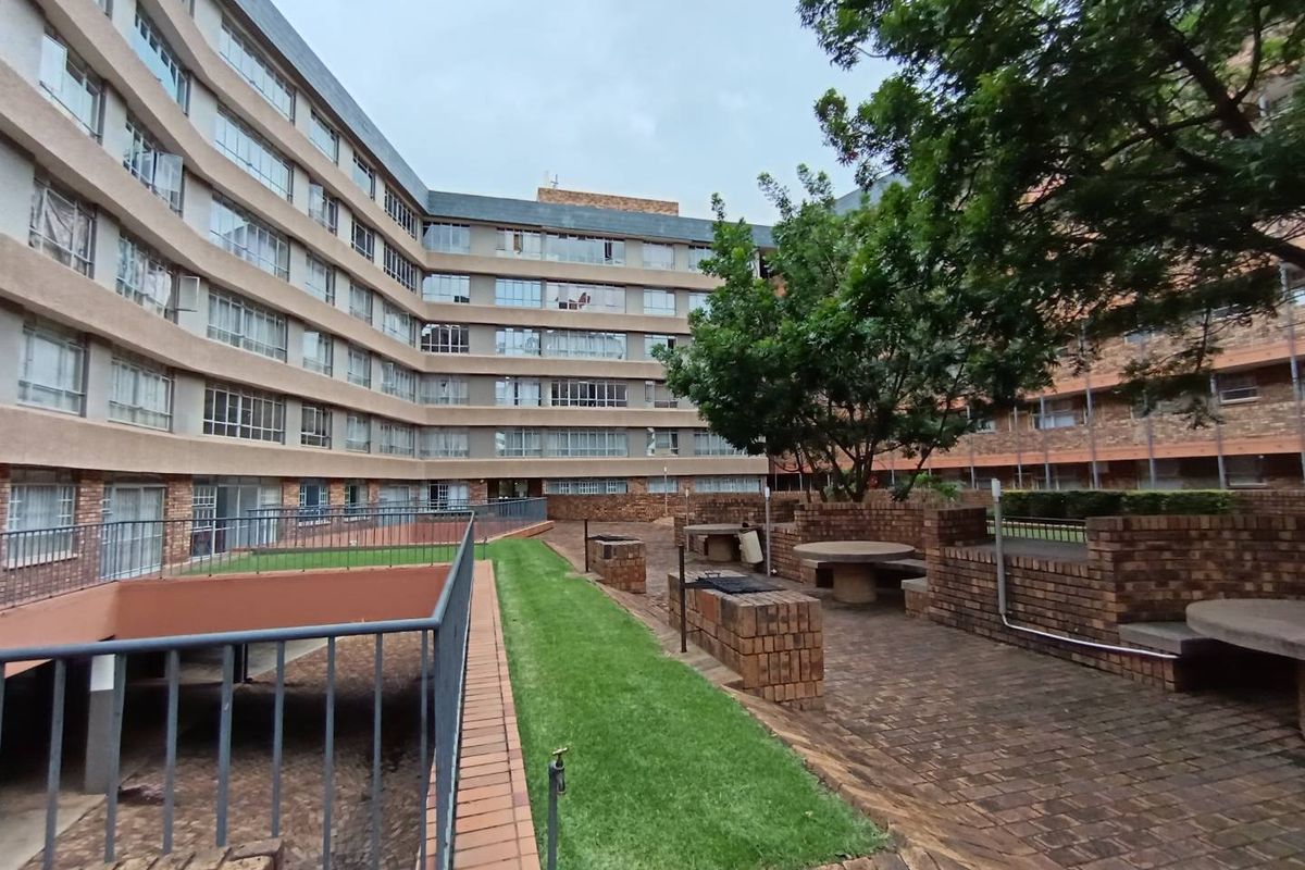 Communal outdoor courtyard area featuring brick paving, built-in brick seating, and landscaped lawn space within an apartment complex.