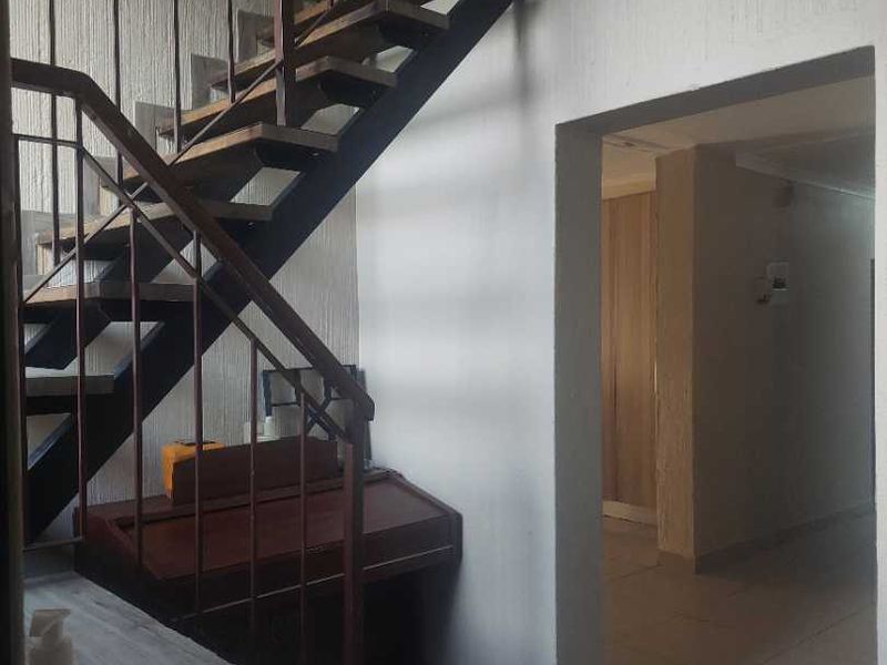 A functional hallway area featuring a metal staircase with a railing, leading to an adjacent room with tiled flooring.