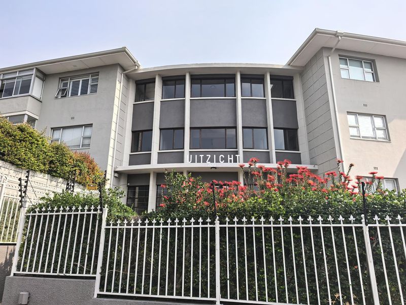 Front elevation of the Uitzicht apartment building, featuring a multi-story concrete facade, aluminium windows, and secure perimeter fencing.