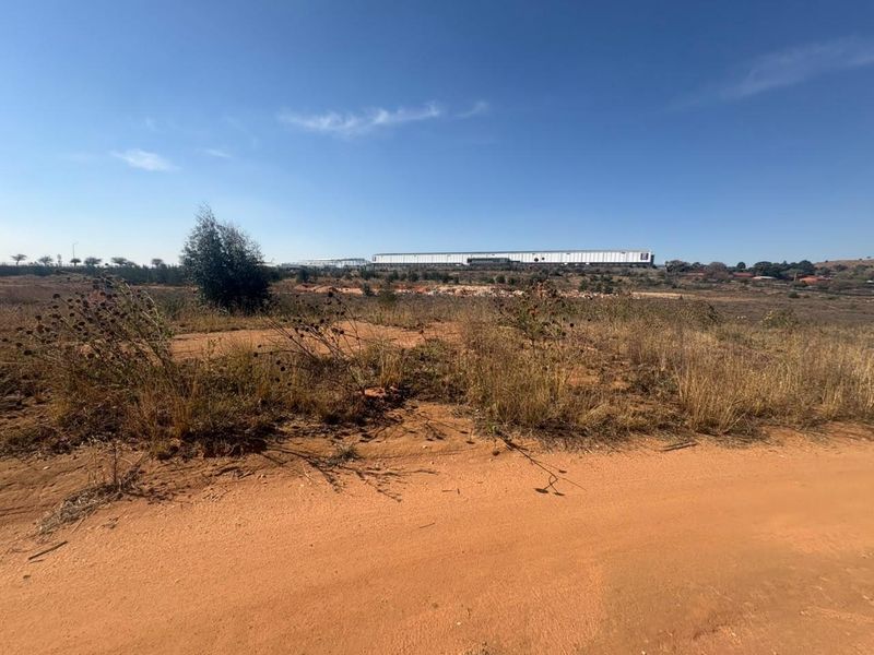 A distant view of a large industrial warehouse facility situated on undeveloped land.