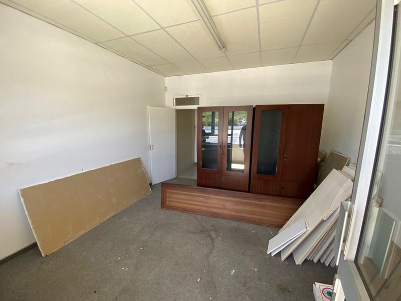 A vacant office space featuring a suspended ceiling, fluorescent lighting, and built-in storage cabinetry, requiring cosmetic updates to improve its professional appeal.