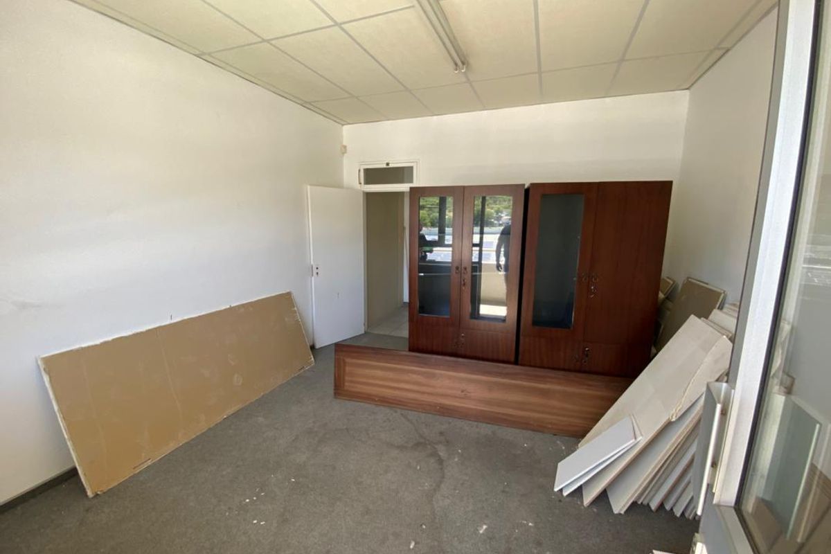 A vacant office space featuring a suspended ceiling, fluorescent lighting, and built-in storage cabinetry, requiring cosmetic updates to improve its professional appeal.