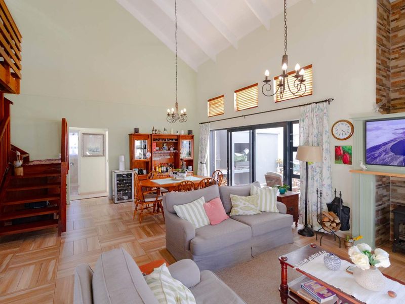 Spacious open-plan living and dining area featuring a vaulted ceiling, stone-clad fireplace, and direct access to the patio through sliding glass doors.