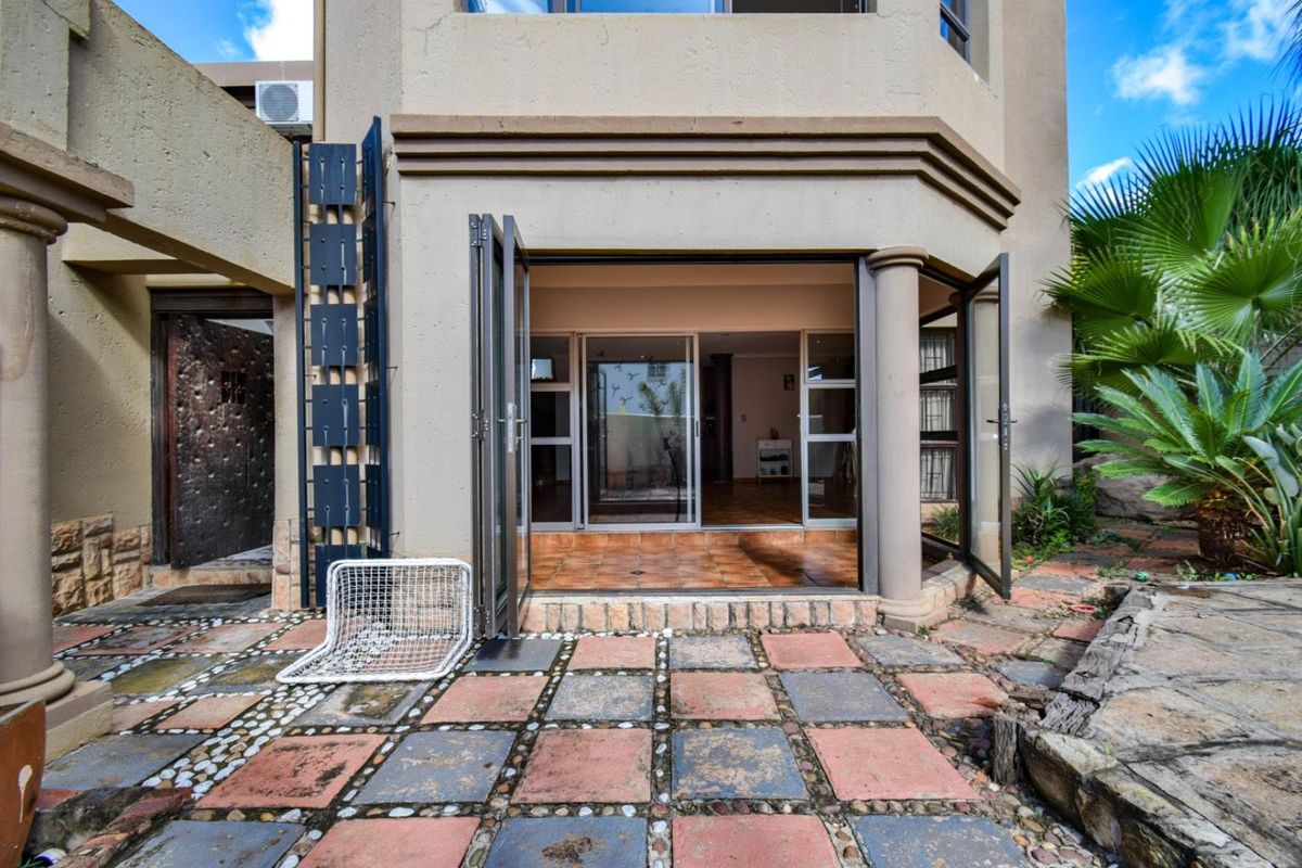 Rear view of the property featuring a paved patio area with bi-fold doors leading into the interior living space.