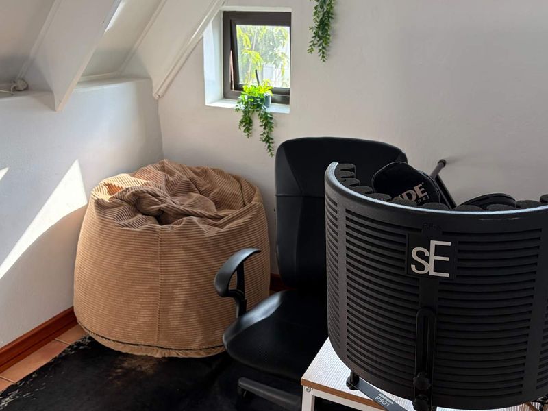 A compact attic-style office space featuring sloped ceilings, tiled flooring, and a small window providing natural light.