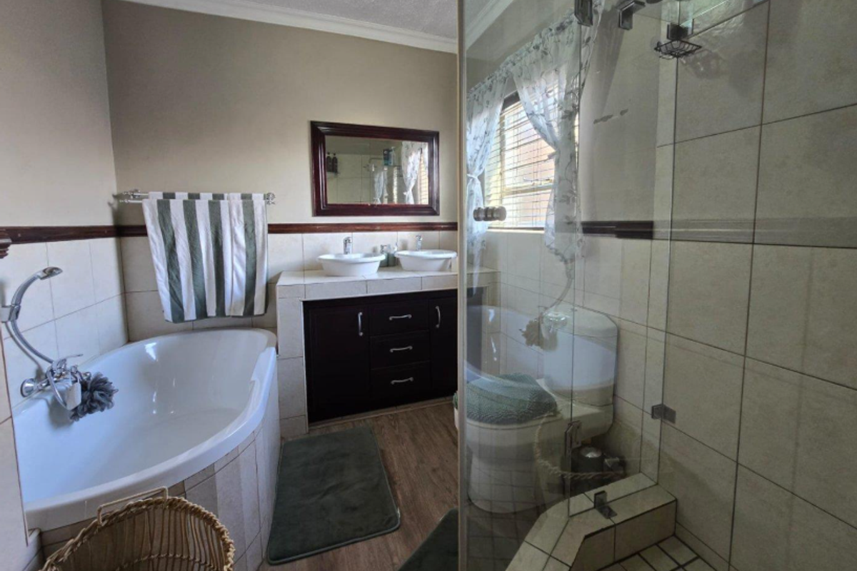 A functional bathroom featuring a corner bathtub, a glass-enclosed shower, and a double vanity with dark wood cabinetry.