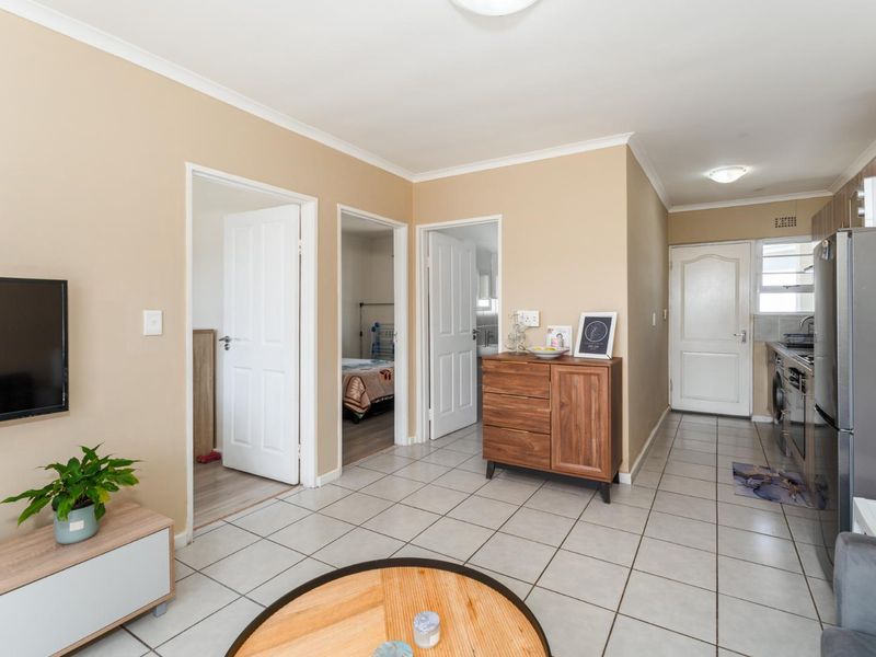 Open plan living area featuring tiled flooring, neutral wall tones, and direct access to the kitchen and adjacent bedroom and bathroom spaces.
