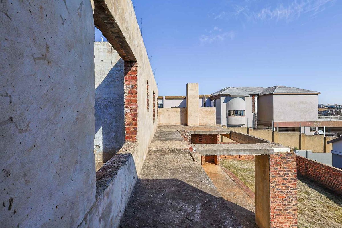 An unfinished residential construction site showing exposed brick and concrete structural elements, offering a blank canvas for completion and custom finishing.