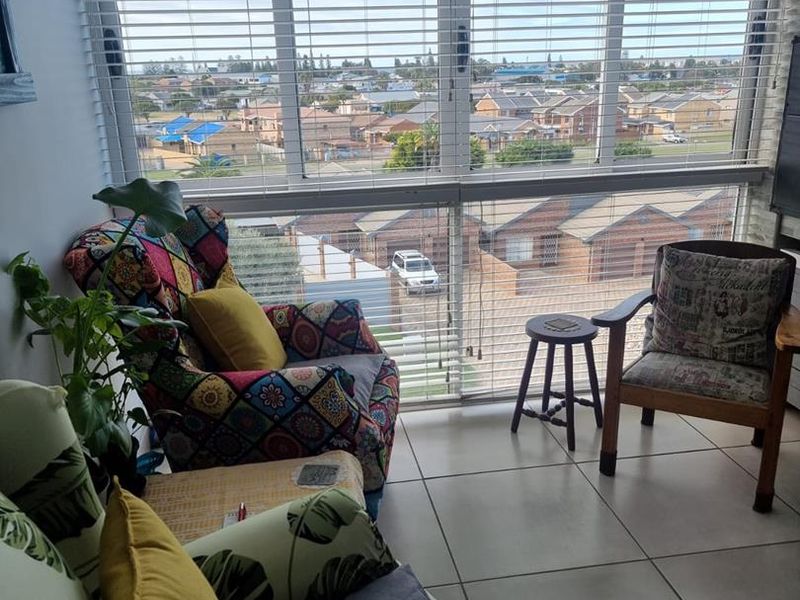 A bright living area featuring large windows with venetian blinds, offering an elevated view of the surrounding residential neighborhood.