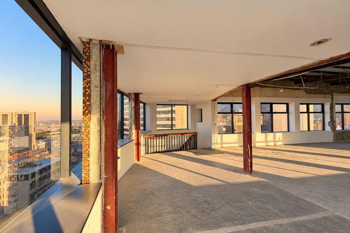 Spacious open-plan commercial interior featuring floor-to-ceiling windows with city views, exposed structural steel columns, and an unfinished ceiling, offering significant potential for custom fit-out.