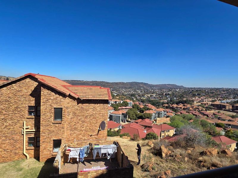 Elevated view overlooking the surrounding residential neighbourhood and landscape, featuring a face-brick townhouse exterior.