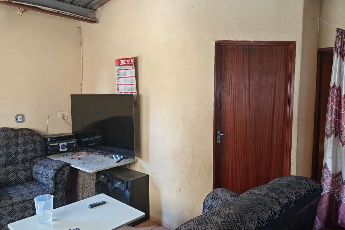 A living room area featuring tiled flooring and a timber door, showing signs of wear on the walls.
