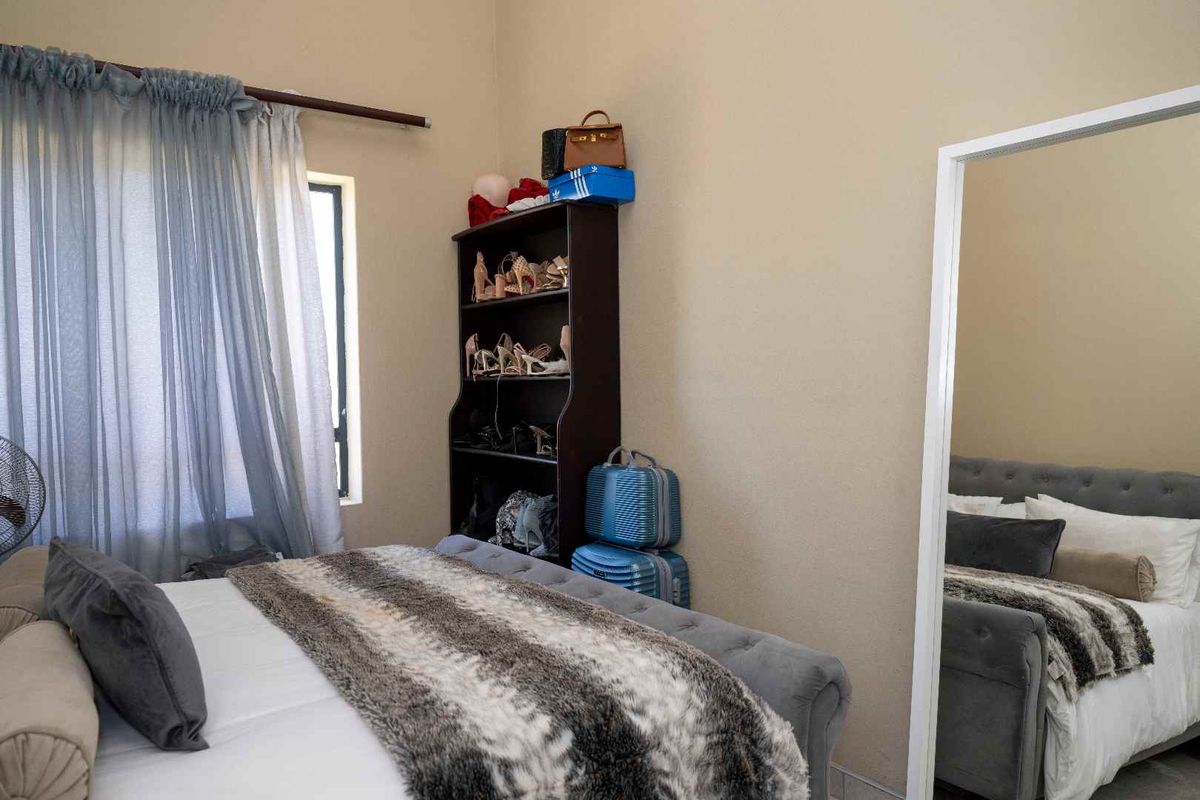 A bedroom featuring a window with curtains and a large floor-standing mirror.