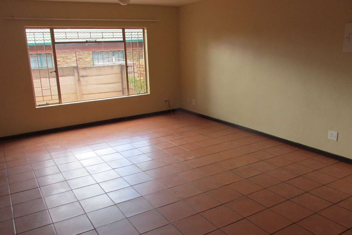 A spacious, empty living room featuring tiled flooring and a large window, providing a blank canvas for potential interior design and renovation.