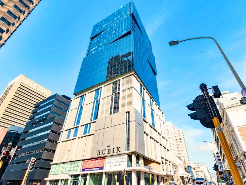 A modern high-rise apartment building featuring a contemporary glass facade and prominent street-level commercial frontage in an urban setting.