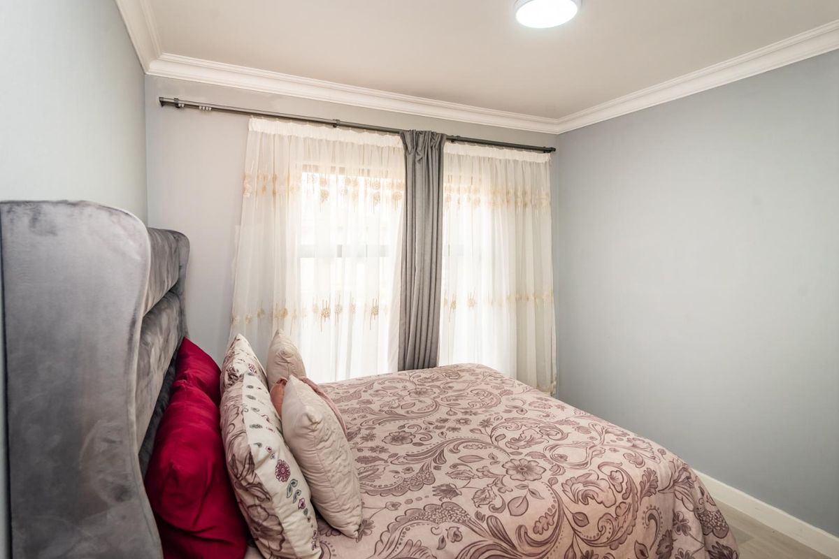 A well-maintained bedroom featuring crown molding and a curtain rod, providing a clean and neutral space.
