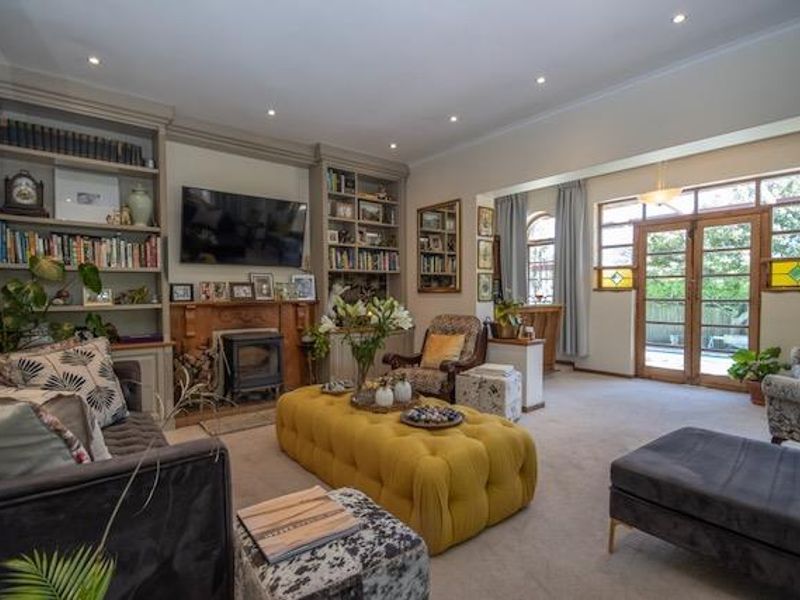 Spacious living room featuring custom built-in shelving, a cozy wood-burning stove, and timber-framed glass doors leading to the outdoor area.