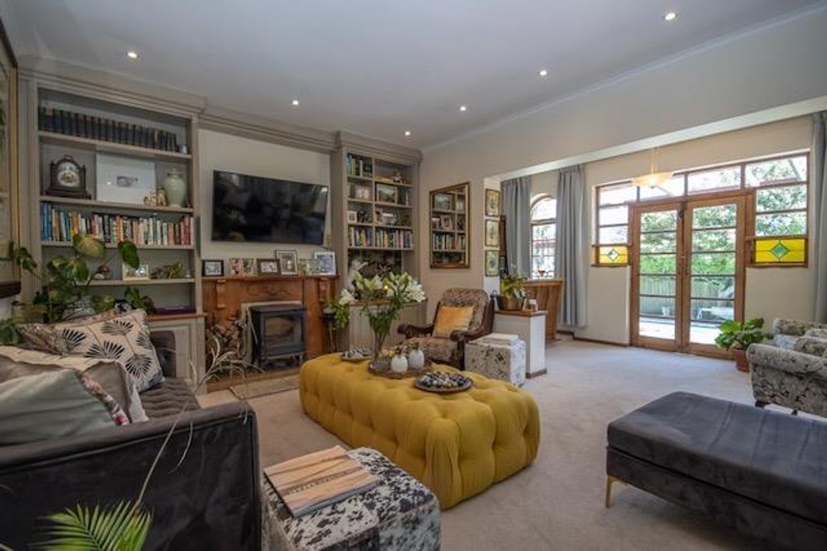 Spacious living room featuring custom built-in shelving, a cozy wood-burning stove, and timber-framed glass doors leading to the outdoor area.