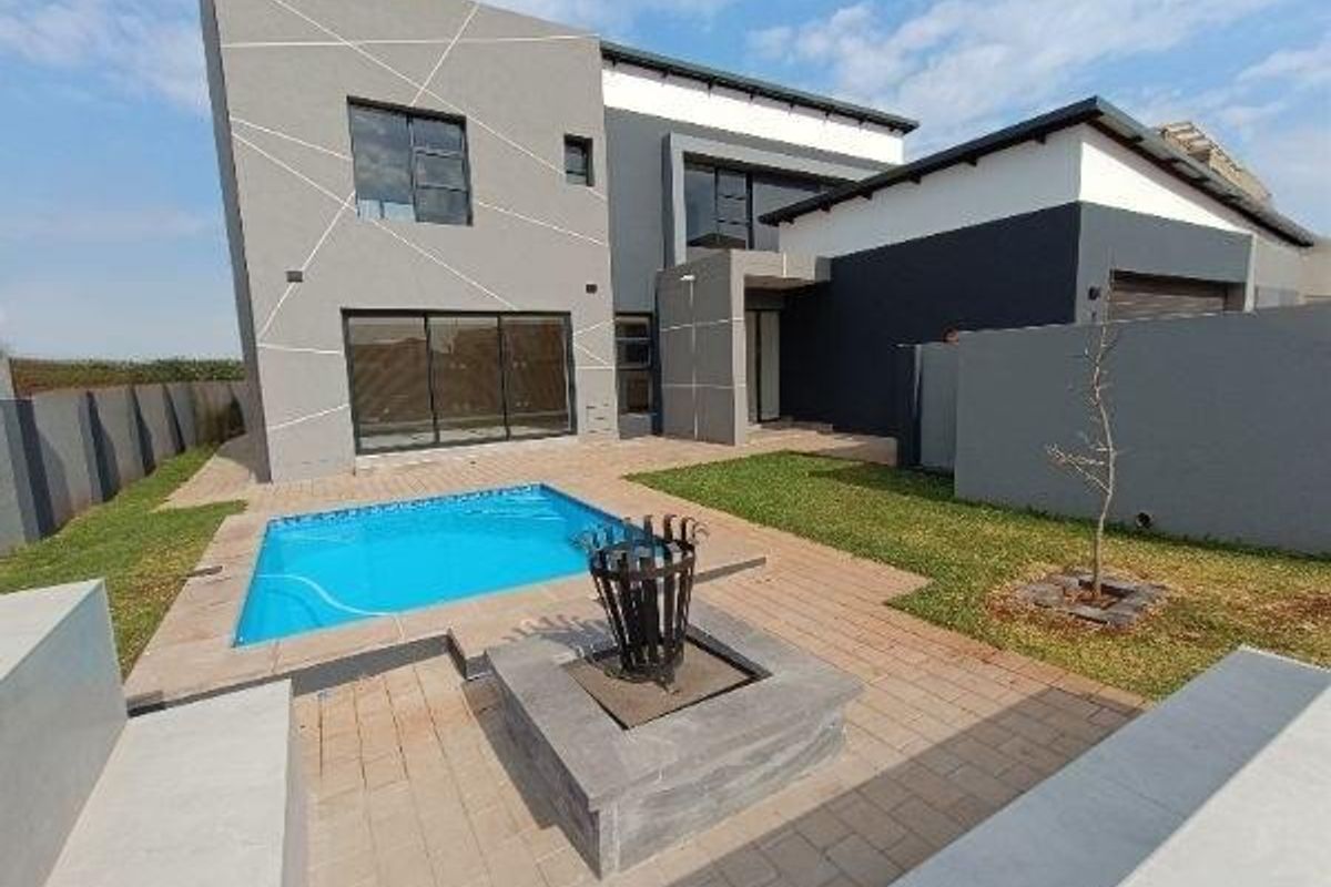 Modern rear exterior featuring a swimming pool, paved patio area with a built-in fire pit, and contemporary architectural facade.