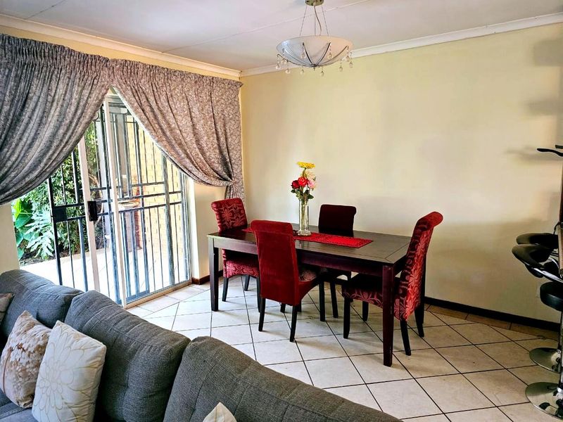 Open plan living and dining area featuring tiled flooring, a pendant light fixture, and a sliding glass door with security gate leading to the exterior.