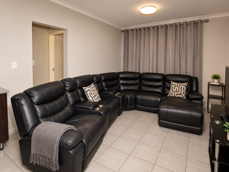 A well-maintained living room featuring neutral tiled flooring, built-in cabinetry with a granite countertop, and a clean, modern aesthetic.