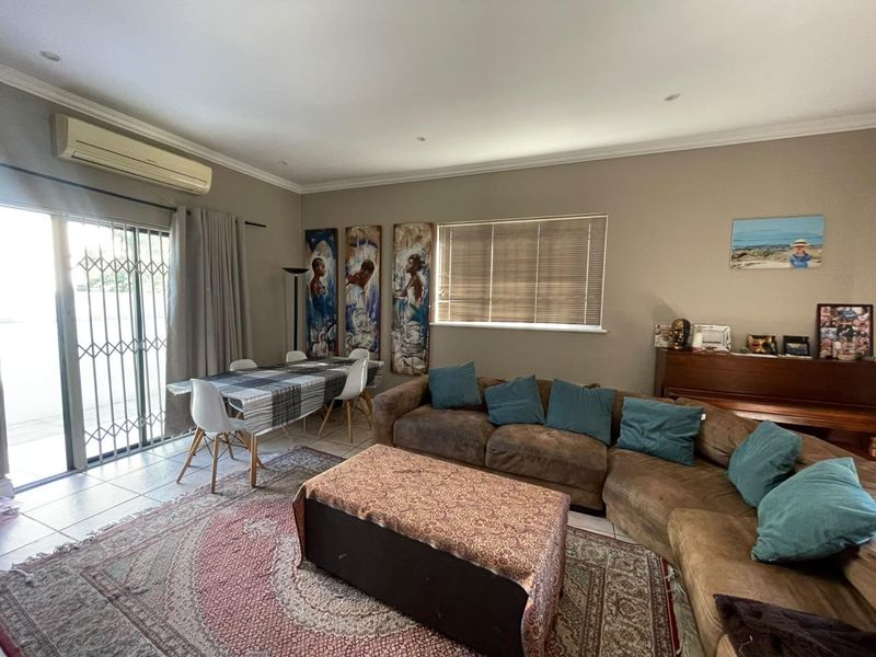 Spacious living area featuring tiled flooring, recessed lighting, and a split-system air conditioner, with direct access to the outdoor area via a sliding glass door.