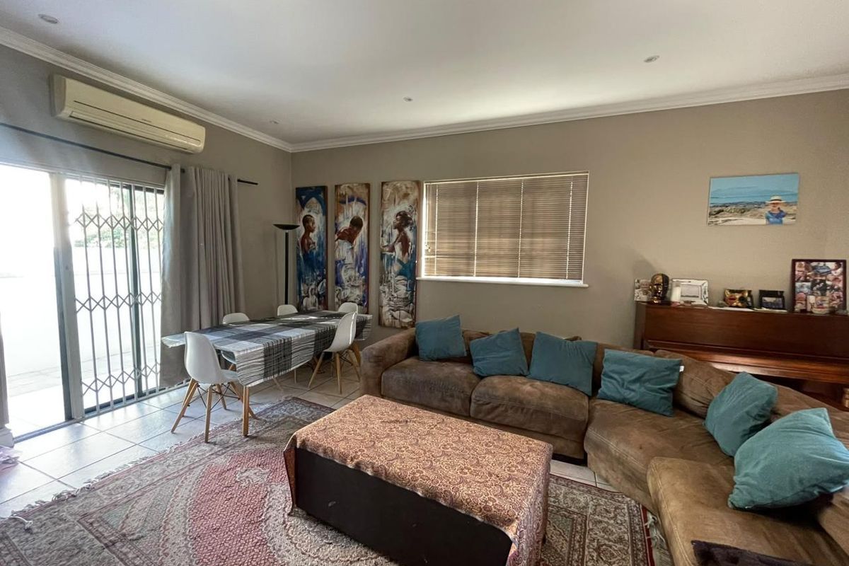 Spacious living area featuring tiled flooring, recessed lighting, and a split-system air conditioner, with direct access to the outdoor area via a sliding glass door.