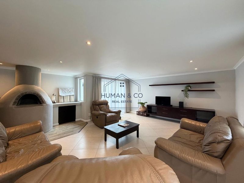 Spacious living room featuring tiled flooring, recessed downlights, floating wall shelves, and a unique built-in pizza oven.