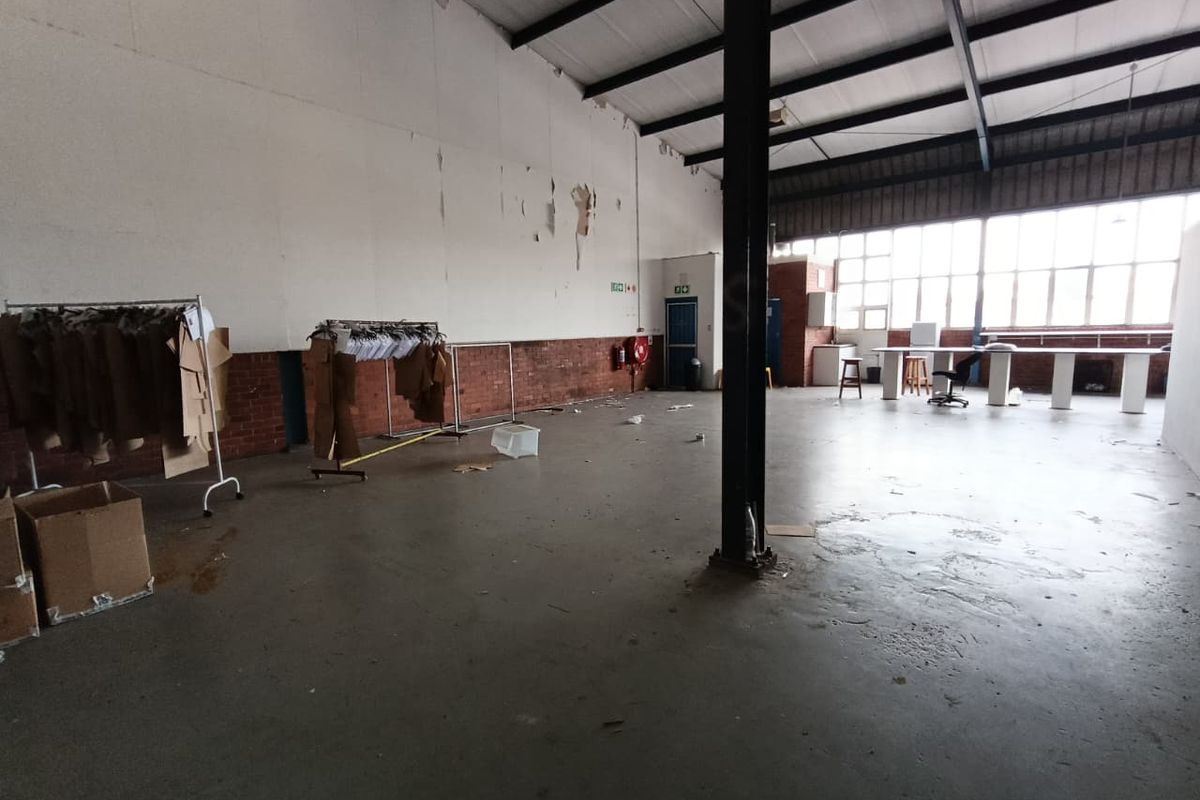 Spacious industrial utility area featuring high ceilings with exposed steel trusses, concrete flooring, and large windows providing ample natural light.
