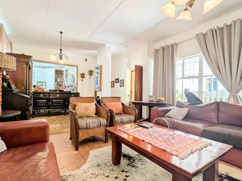 A spacious living room featuring tiled flooring, large windows with curtain tracks, and overhead lighting, providing a comfortable and functional living space.