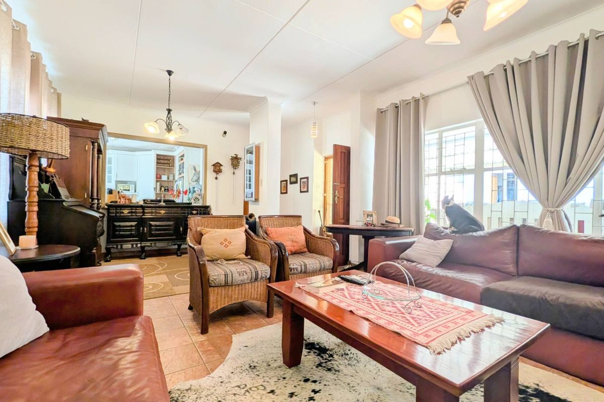 A spacious living room featuring tiled flooring, large windows with curtain tracks, and overhead lighting, providing a comfortable and functional living space.