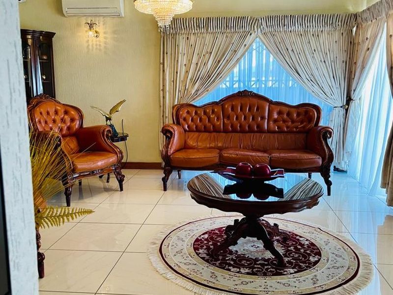 A well-maintained living room featuring polished tiled flooring, a crystal chandelier, and a wall-mounted split-system air conditioner.